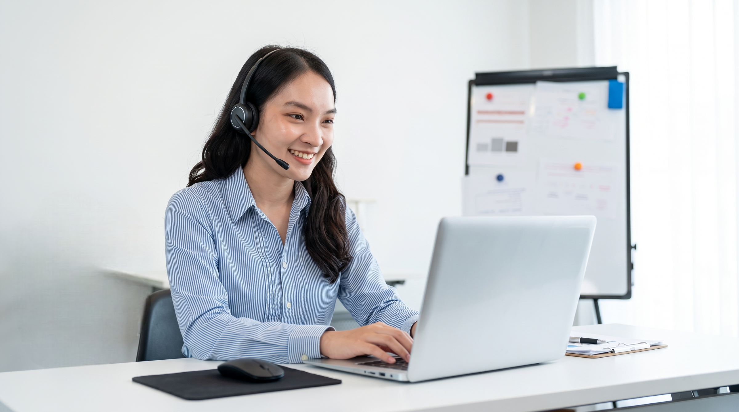 Remote candidate support coordinator working on a laptop with a headset