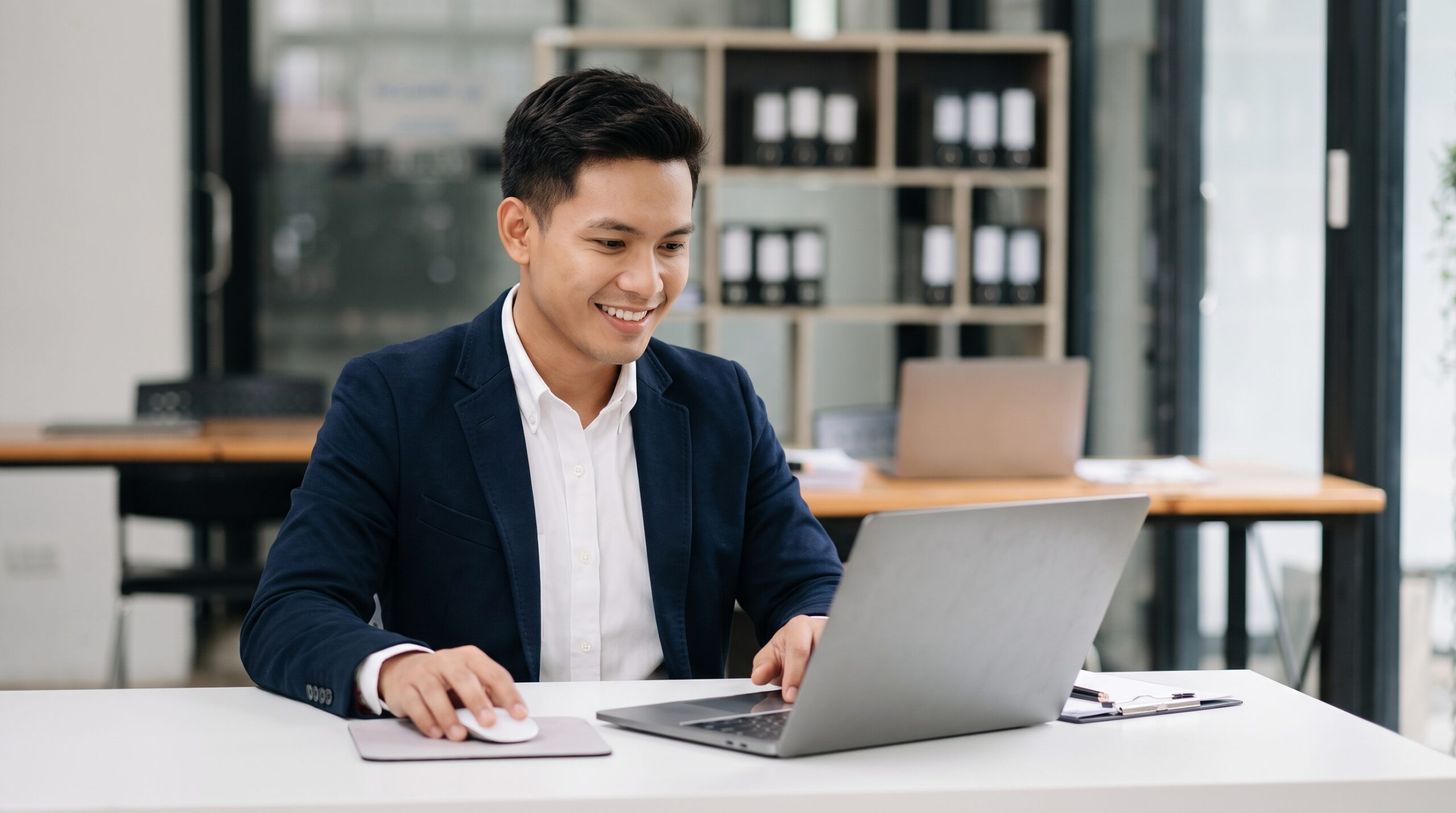 Professional remote governance officer working on a laptop at a white desk in a modern office setup