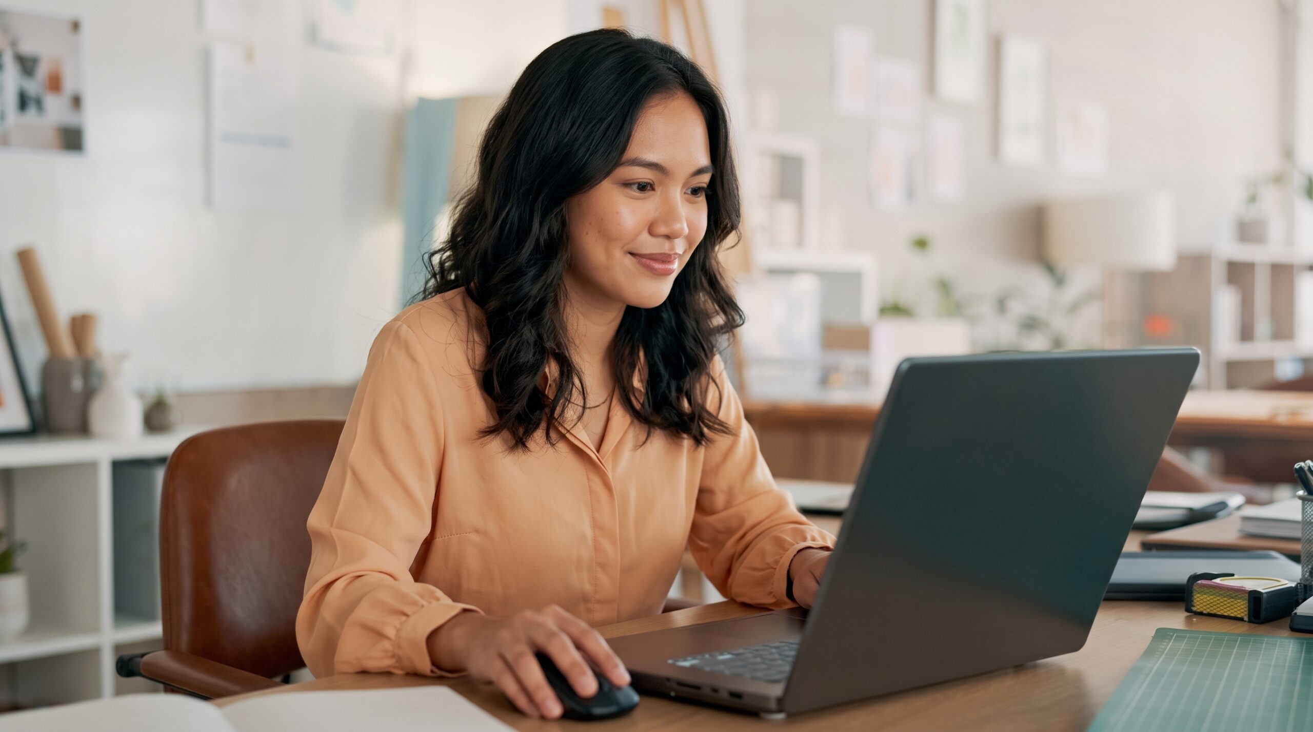 filipina professional focused on a laptop screen while working as a creative strategist remote